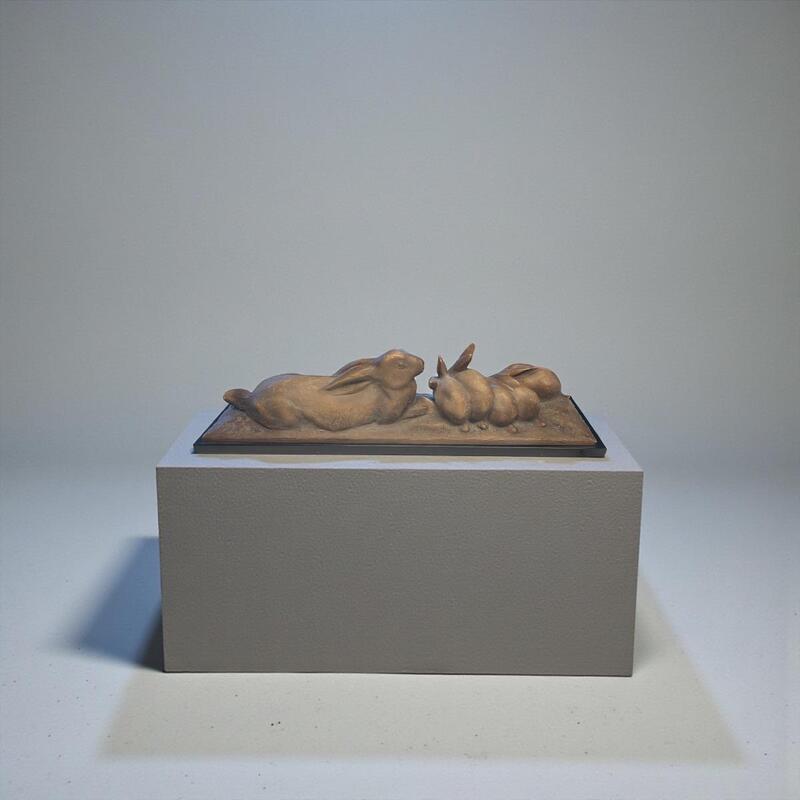 Terracotta sculpture of a family of hares on black marble